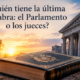 Edificio parlamentario y tribunal enfrentados simbólicamente sobre un ejemplar de la Constitución.